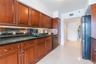 Kitchen featuring raised-panel wood cabinetry, black countertops, mirrored backsplash, under-cabinet lighting, and black appliances