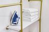 Wall-mounted storage unit featuring gold-tone metallic piping and white shelving