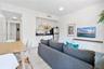 White shaker-style cabinetry, dark stone countertops, tile flooring, and wall-mounted floating shelf