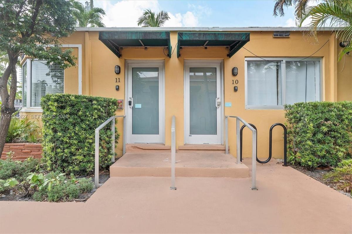 Exterior facade featuring two glass-paneled entry doors, metal awnings, and concrete steps with metal handrails