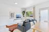 Neutral-toned interior featuring large-format tile flooring, a horizontal wall-mounted floating shelf, a multi-pane sliding window, and a glass-panele
