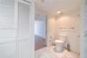 Bathroom featuring white louvered closet doors, stone-patterned tile flooring, a standard-profile toilet, and polished metal wall-mounted towel bars