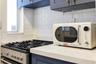 Kitchen featuring dark blue cabinetry with brushed gold hardware, quartz countertops, white subway tile backsplash, and a stainless steel gas range