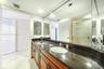 Vanity featuring a dark stone countertop, an integrated oval basin, warm-toned wood cabinetry, a full-width wall mirror, and recessed lighting
