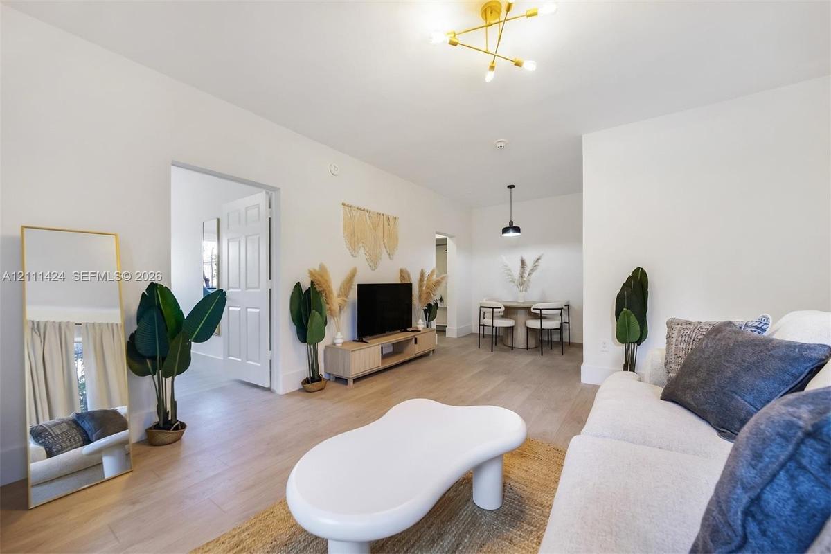 Open-concept interior featuring light wood-finish flooring, a multi-arm brass finish ceiling fixture, and a neutral color palette