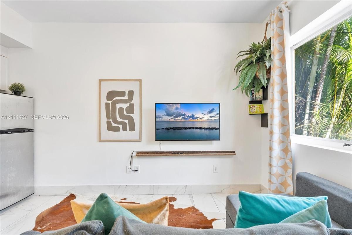 Large window, stone-finish tile flooring, and wall-mounted wooden shelf