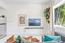 Large window, stone-finish tile flooring, and wall-mounted wooden shelf