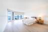 Expansive living area featuring floor-to-ceiling windows, light-toned wood-finish flooring, and an oceanic backdrop