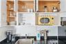 White cabinetry with light-finish interior shelving, black stone-surface countertops, undermount stainless steel sink, and integrated cooktop