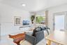 Bright living area featuring large-format stone-finish tile flooring, a wall-mounted display shelf, and a sliding glass exterior door
