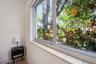 Large sliding window with a tiled sill, featuring white walls and exterior tropical foliage