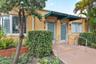 Stucco exterior featuring dual entryways with metal awnings, bay window, and concrete step access with metal handrails