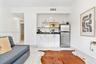 Kitchenette featuring white cabinetry, dark stone countertops, stainless steel refrigerator, and large-format tile flooring