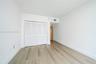 Room featuring wood-finish flooring, white walls, and a closet with bifold louvered doors