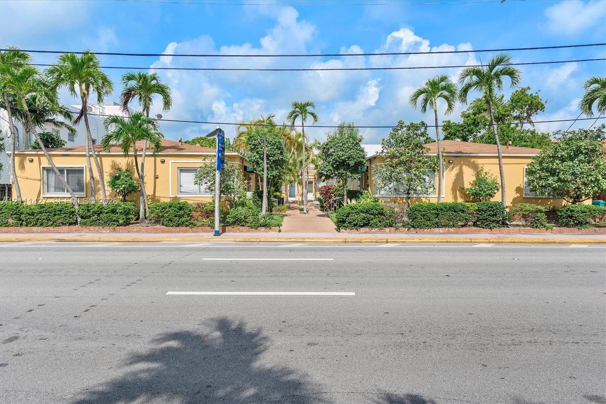 Single-story exterior featuring a painted stucco facade, low-slope rooflines, and mature palm tree landscaping
