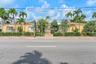 Single-story exterior featuring a painted stucco facade, low-slope rooflines, and mature palm tree landscaping