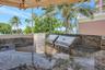 Outdoor BBQ kitchen featuring stone countertops, dual stainless steel built-in grills, a covered structure, and water views