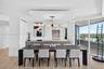 Open-concept kitchen featuring flat-panel cabinetry, light-toned stone counters, wood look plank porcelain flooring, tray ceiling with recessed lighti