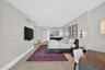 Spacious room featuring wood look plank porcelain flooring, neutral wall tones, and wall-mounted light fixtures. View toard primary bathroom and large