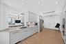 Kitchen featuring flat-panel cabinets, light-toned stone counters, stainless appliances including a wall ovens, recessed lighting, and wood look plank