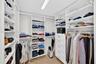 View toward shorter side of the custom walk-in closet featuring floor-to-ceiling white shelving, integrated clothing rods, stacked drawer storage, and