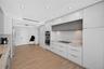 Modern kitchen featuring matte finish cabinets, stone counters & backsplash, built-in stainless steel double wall ovens, cooktop, and wood look plank 
