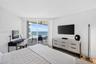 Full-height sliding glass doors opening to a private balcony, wood look plank porcelain flooring, and expansive ocean views. Double layered (light fil