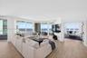 Expansive living area (and bedroom to the right, currently being used as a den) w/ hurricane impact rated floor-to-ceiling windows, wood look plank po