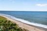 Direct oceanfront setting with sandy beach access, native coastal vegetation, and expansive horizon