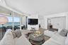 Living area featuring floor-to-ceiling glass panel walls, wood look plank porcelain flooring, integrated lighting, and a glass-railed balcony for more