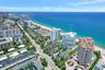 Aerial perspective of a multi-story residential building located on the coastline, featuring an on-site tennis court, swimming pool, and direct proxim