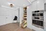 Custom cabinets featuring a floor-to-ceiling pull-out pantry with wood pull out and soft-close tongue & groove drawers, integrated stainless steel Bos