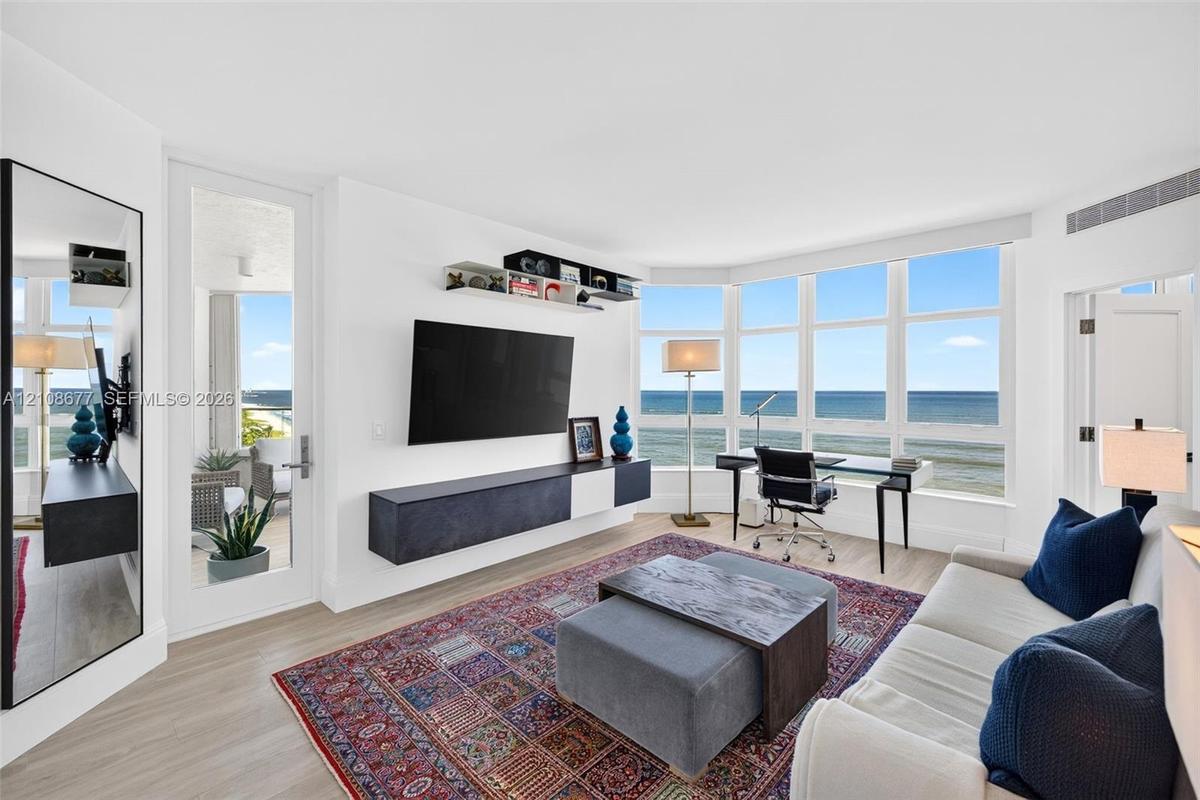 Bedroom / living space featuring expansive floor-to-ceiling windows, wood look plank porcelain flooring, and a wall-mounted floating storage console. 