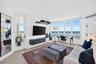 Bedroom / living space featuring expansive floor-to-ceiling windows, wood look plank porcelain flooring, and a wall-mounted floating storage console. 