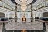 Grand lobby foyer featuring an expansive polished stone floor, a suspended multi-tiered crystal chandelier, a multi-faceted coffered ceiling with rece
