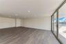 Open-concept living space featuring wood-finish flooring, recessed ceiling lighting, and floor-to-ceiling glass sliding doors leading to an outdoor ba