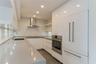 Kitchen featuring white high-gloss cabinetry, solid surface countertops, stainless steel appliances, open shelving, and wood-finish flooring