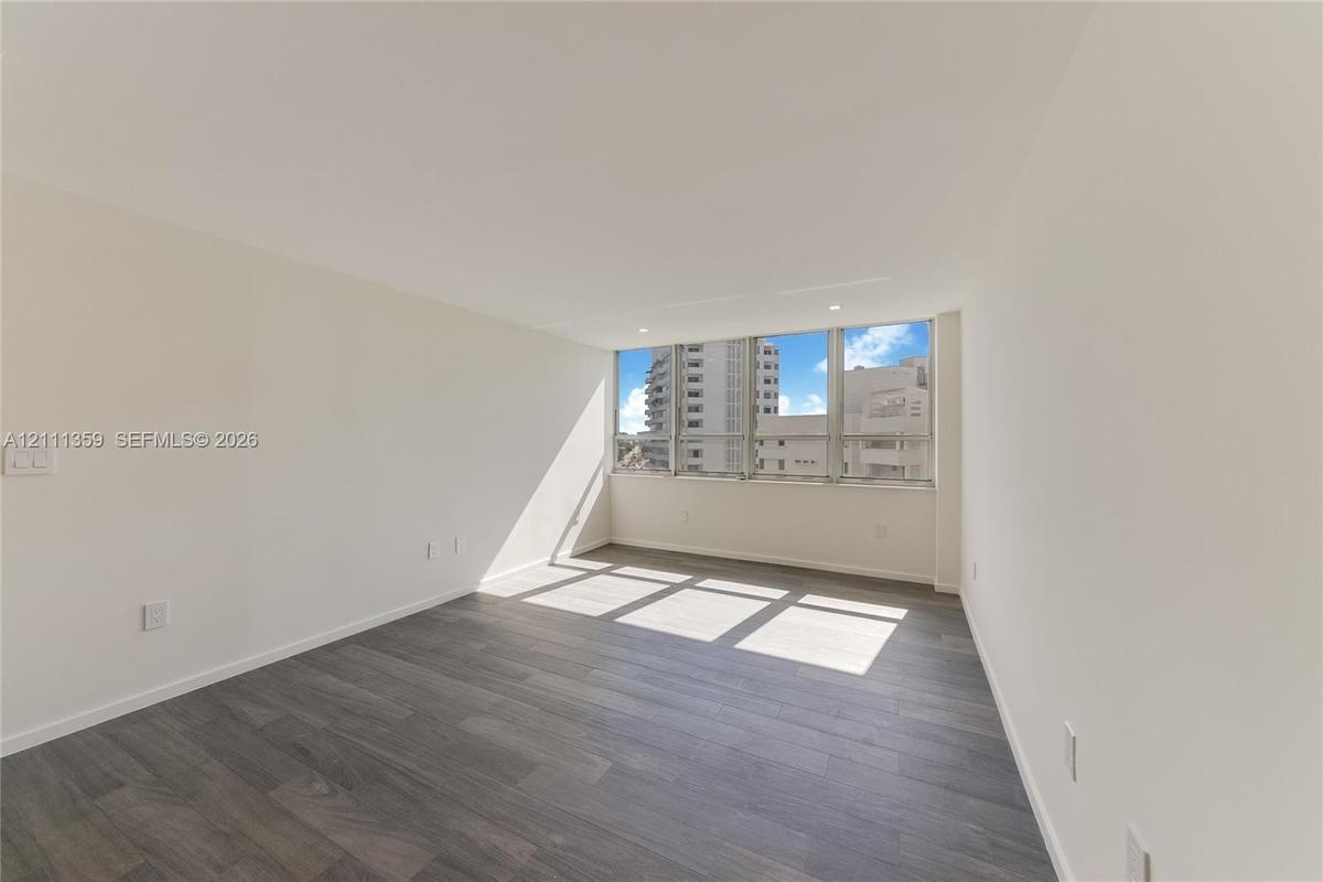 Neutral interior space featuring wood-finish flooring, floor-to-ceiling windows, and recessed ceiling lighting