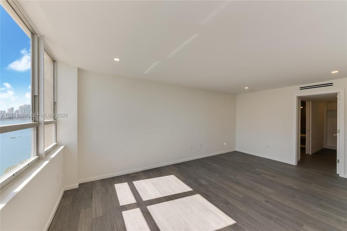 Interior space featuring wood-finish flooring, floor-to-ceiling windows, recessed lighting, and a neutral color palette