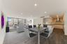 Open-concept living space featuring wood-finish flooring, recessed lighting, floor-to-ceiling glass sliding doors, and a kitchen equipped with flat-pa
