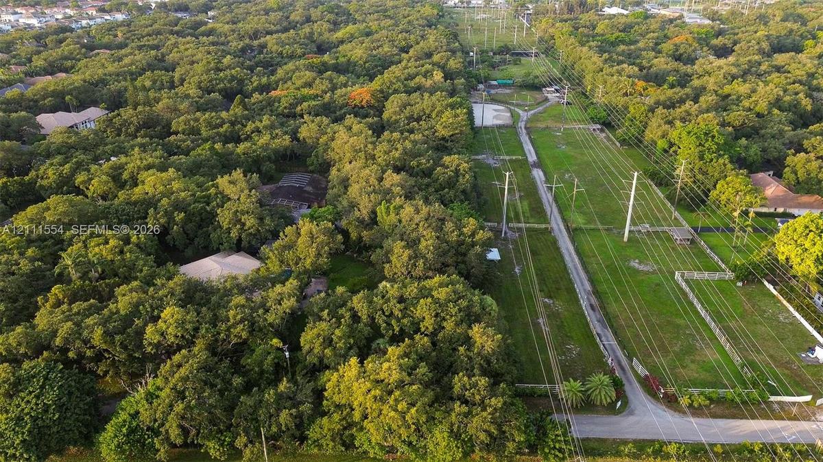 Aerial perspective of expansive wooded acreage featuring mature canopy coverage and cleared grassy terrain