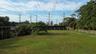 Expansive lot featuring a manicured lawn, mature trees, and white post-and-rail fencing