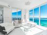 Floor-to-ceiling windows, white tile flooring, sliding glass door, white geometric ceiling fixture, and exterior balcony