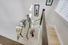 Staircase featuring glass panel railings, wood-finish handrails, multi-tiered sculptural pendant lighting, and light-toned flooring