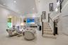 Open-concept living space featuring a recessed ceiling with integrated lighting, built-in linear fireplace with stone-finish surround, staircase with 