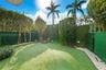 Private outdoor area featuring synthetic turf, perimeter privacy screening, mature landscape hedging, and decorative stone borders