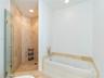 Walk-in shower featuring tile surrounds and a glass enclosure, paired with a deep soaking tub featuring tile surrounds and chrome-finish fixtures