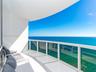Covered balcony featuring white tiled flooring and a glass panel railing with an expansive ocean horizon