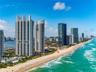 Coastal high-rise buildings situated along a sandy beach shoreline with direct ocean access