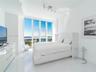 Floor-to-ceiling windows featuring panoramic urban and water scenery, polished stone tile flooring, and adjustable track lighting